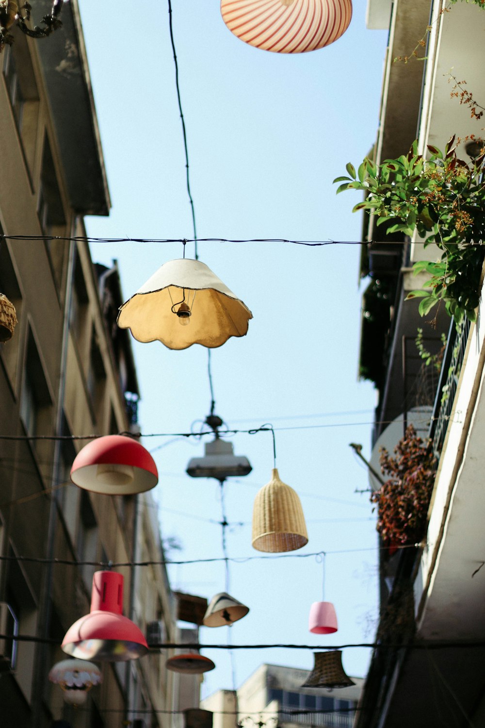 fotografia ad angolo basso di lampade di colori assortiti appese al filo tra gli edifici bianchi