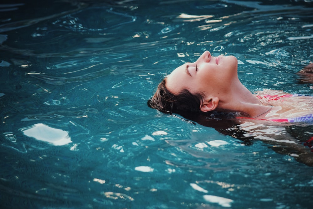 Close-up of a woman floating on her back in azure water