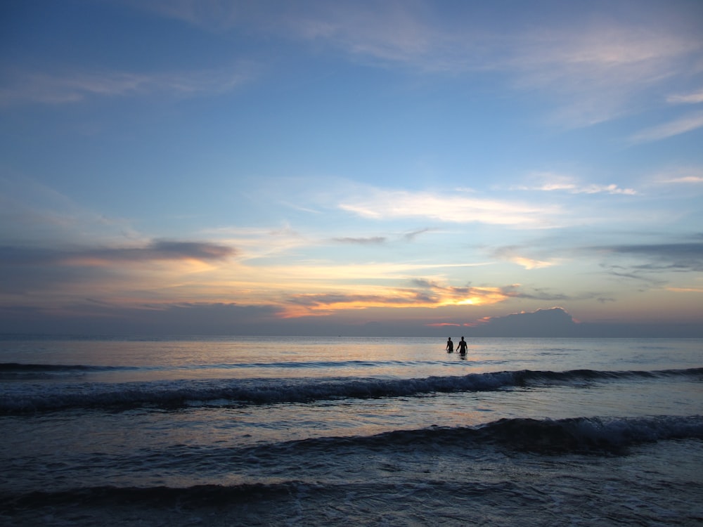 silhouette photography of two person in body of water