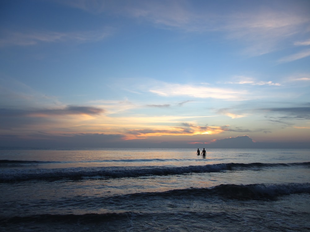 Silhouettenfotografie von zwei Personen im Gewässer