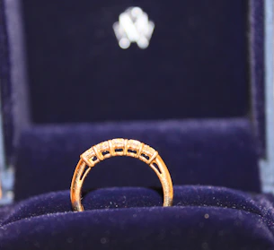 A sparkling gold ring with intricate detailing displayed on a velvet cushion
