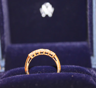 Elegant display of diamond and platinum rings sparkling on a velvet cushion with royal blue background.