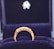 A gold ring with a row of small, sparkling diamonds is prominently displayed against a plush, dark blue velvet background. The ring appears elegant and is encased in a box lined with the same blue velvet, suggesting it is a piece of fine jewelry.