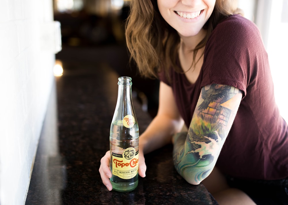 Offenes Foto einer Frau, die eine Flasche mit breitem Lächeln hält