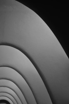 Curved, layered architectural elements create a series of overlapping arches with a smooth texture and gradient shading from light to dark.