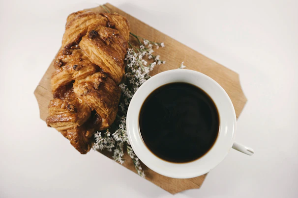 Freshly baked croissants arranged on a wooden board with a dusting of powdered sugar