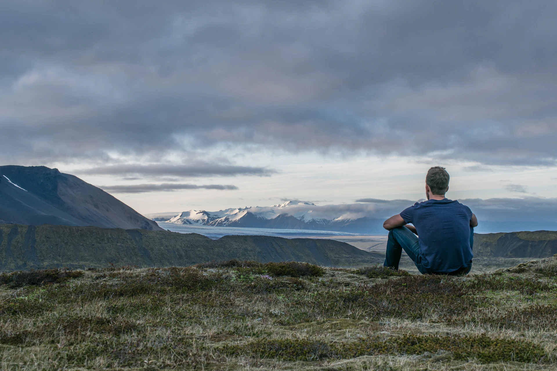 A man sitting on the top of a mountain overlooking a vast landscape.