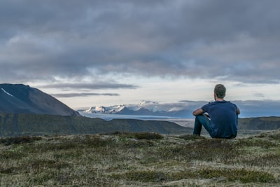 man sitting in the top of the mountain contemplative zoom background