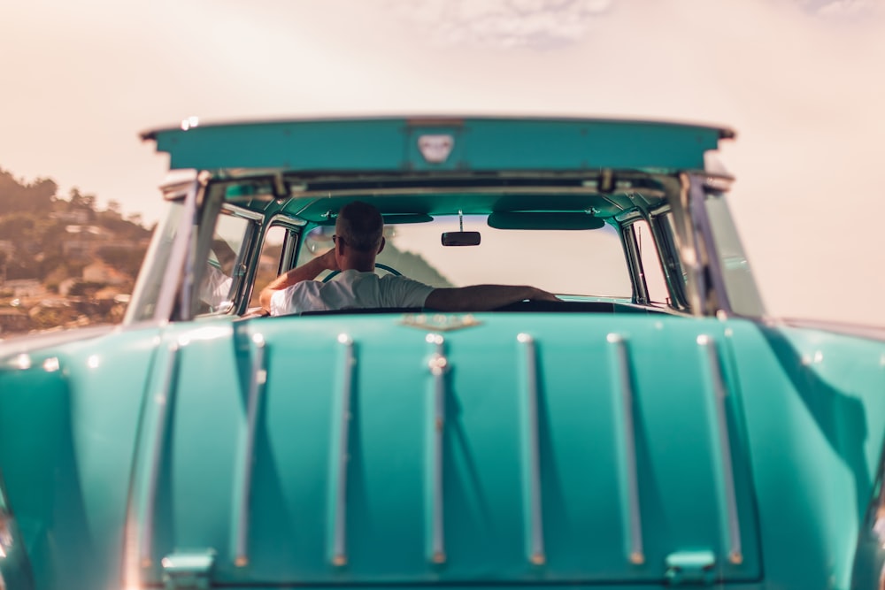 selective focus photography of person riding teal car