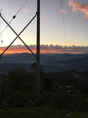 A scenic Montana mountain landscape with a ham radio antenna silhouetted against a colorful sunset.