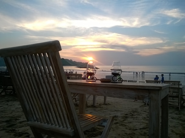 Wide shot of the restaurant’s sandy beach setting at sunset, with two terraces glowing warmly.