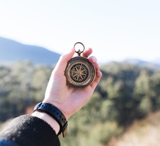 person holding compass selective focus photography