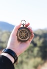 person holding compass selective focus photography