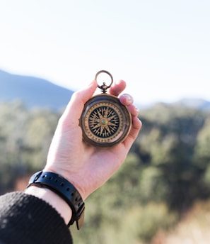 person holding compass selective focus photography