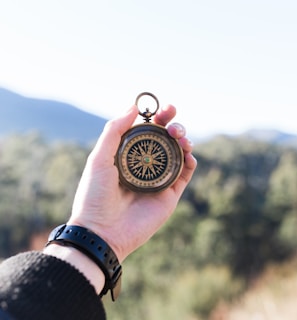 person holding compass selective focus photography