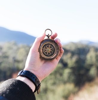 person holding compass selective focus photography