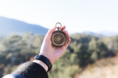 person holding compass selective focus photography journey google meet background