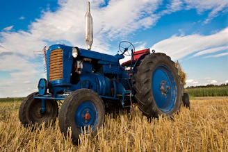 Well-used tractor with fresh paint parked in a sunny field ready for work