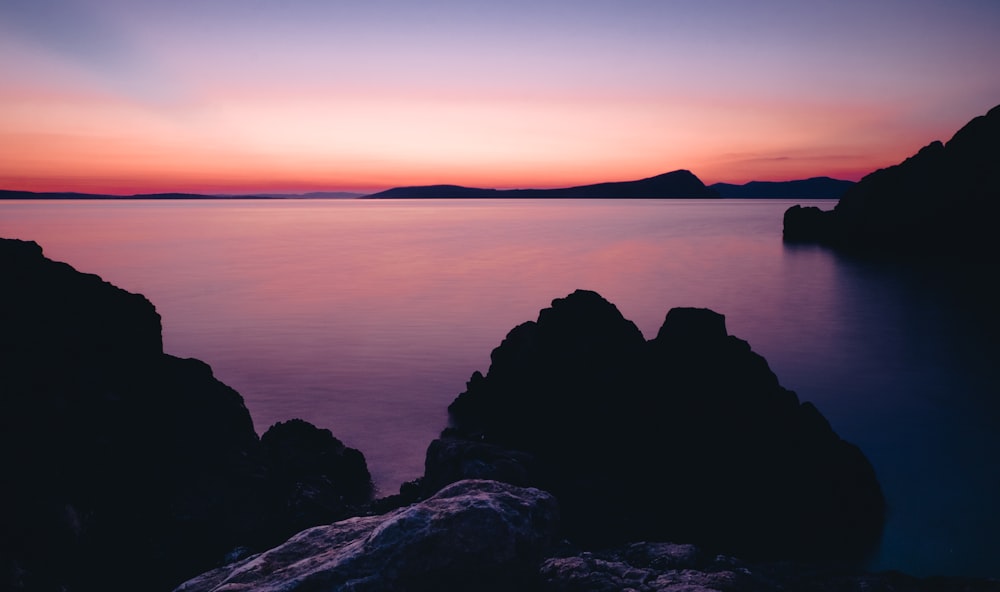 two black rock formation surrounded by body of water