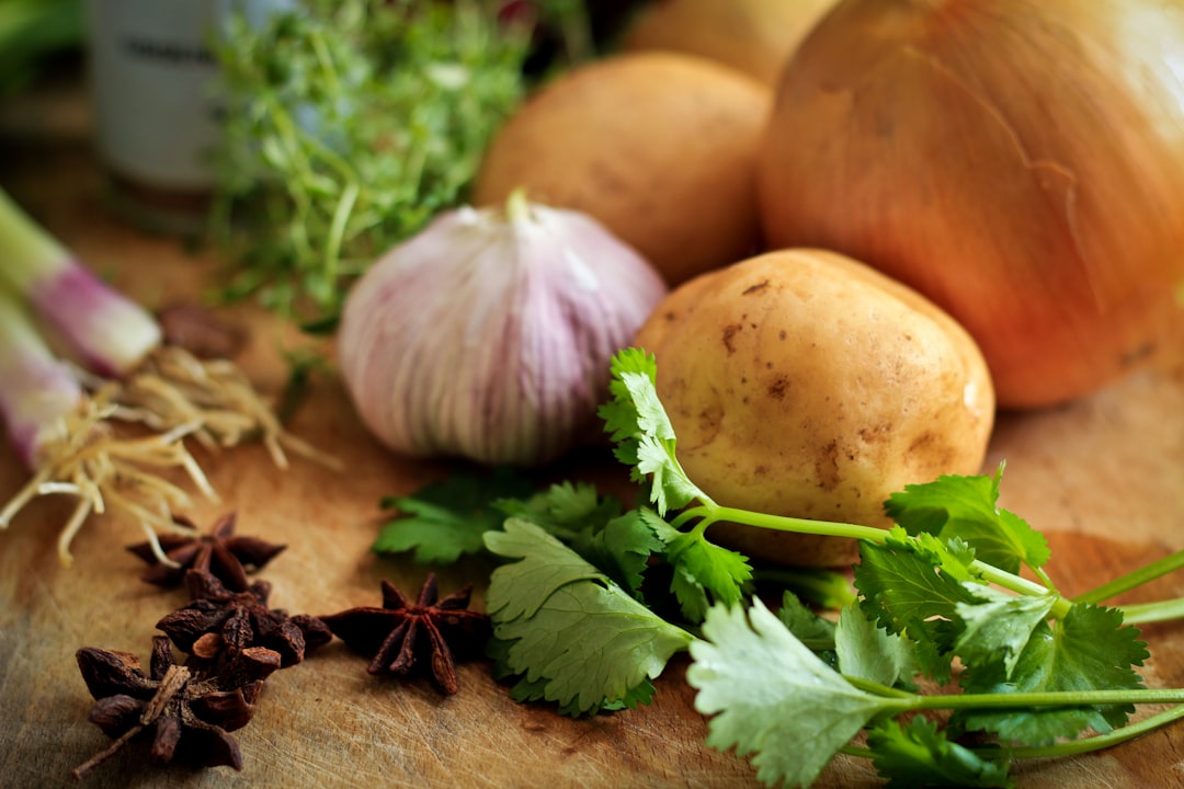 Onions, potatoes, cilantro, and spices on a cutting board