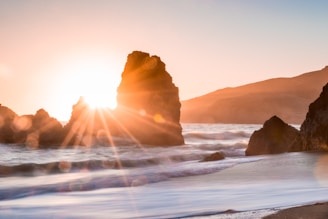 golden hour photography of rock formation on body of water