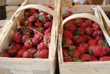 Baskets filled with ripe strawberries and blackberries on a rustic wooden table.