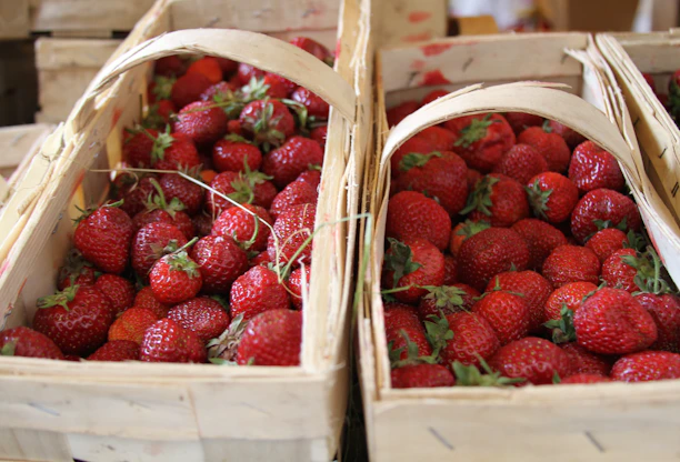 A basket full of ripe strawberries ready for delivery on a wooden table.