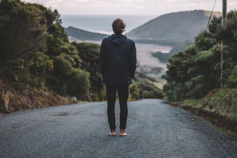 man standing on road near river