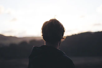person wearing hoodie watching mountain view during golden hour