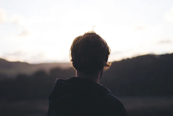 person wearing hoodie watching mountain view during golden hour
