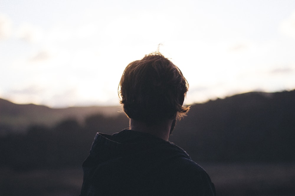 person wearing hoodie watching mountain view during golden hour