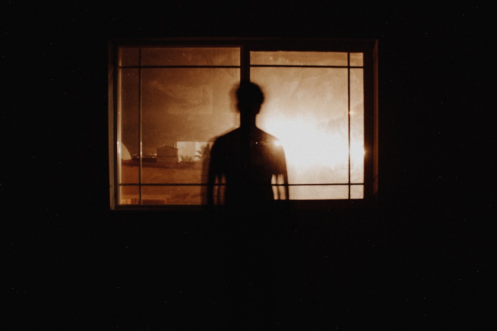 silhouette fotografia di persona davanti alla finestra