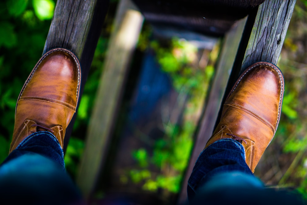 homme portant des chaussures habillées en cuir marron marchant sur du bois brun