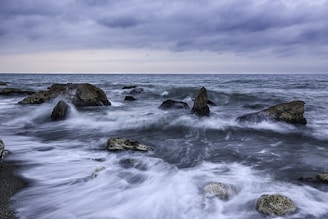 photo of a dancing waves with rocks