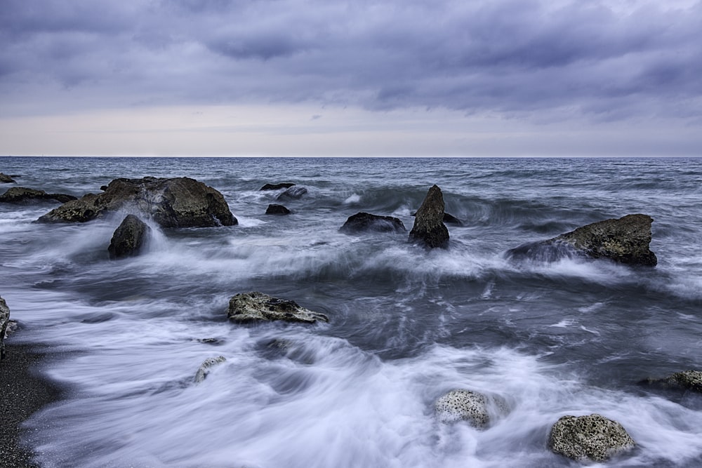 foto de una ola bailando con rocas