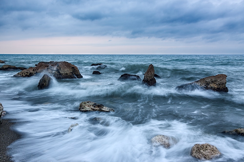 photo of a dancing waves with rocks
