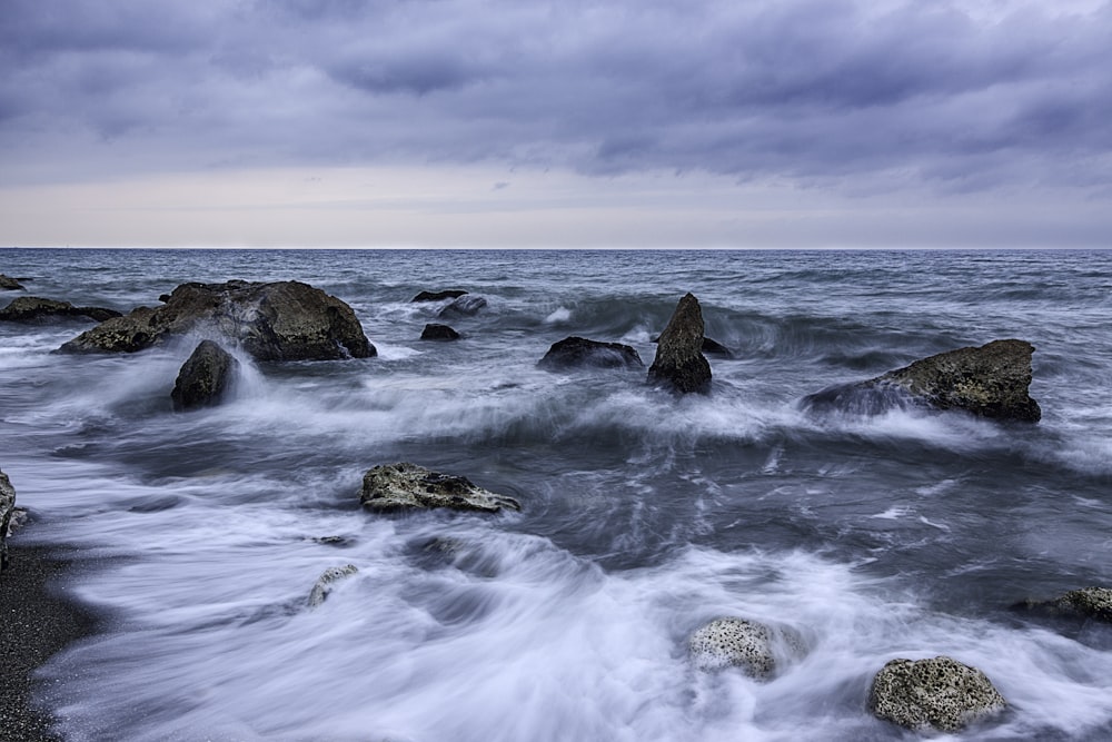 photo of a dancing waves with rocks