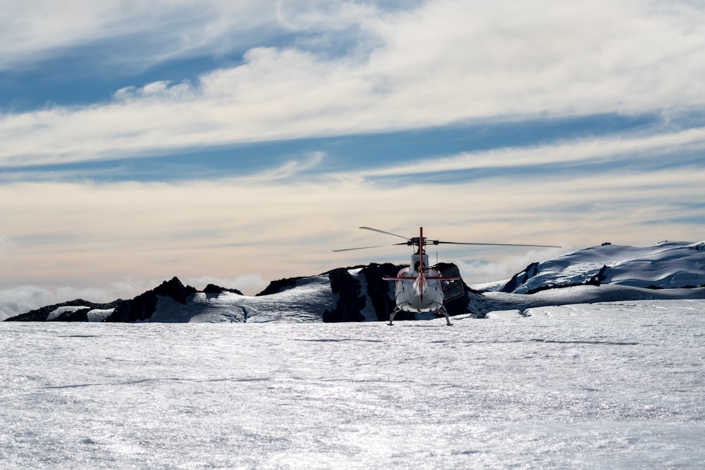 Weißer und roter Hubschrauber fliegt über Gewässer