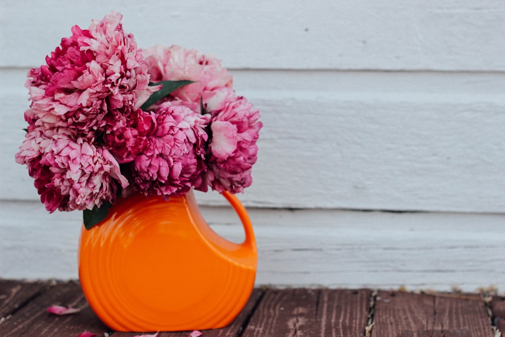 pink flowers on orange ceramic vase