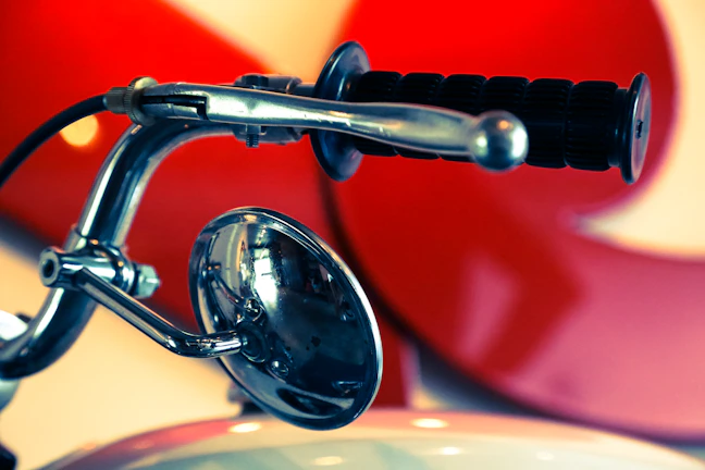 Close-up of biker's hand gripping a skull-emblazoned motorcycle handlebar under red neon light.