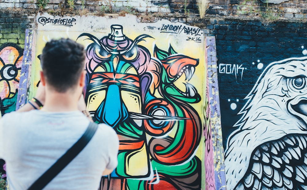 um homem em pé na frente de uma parede coberta de grafite