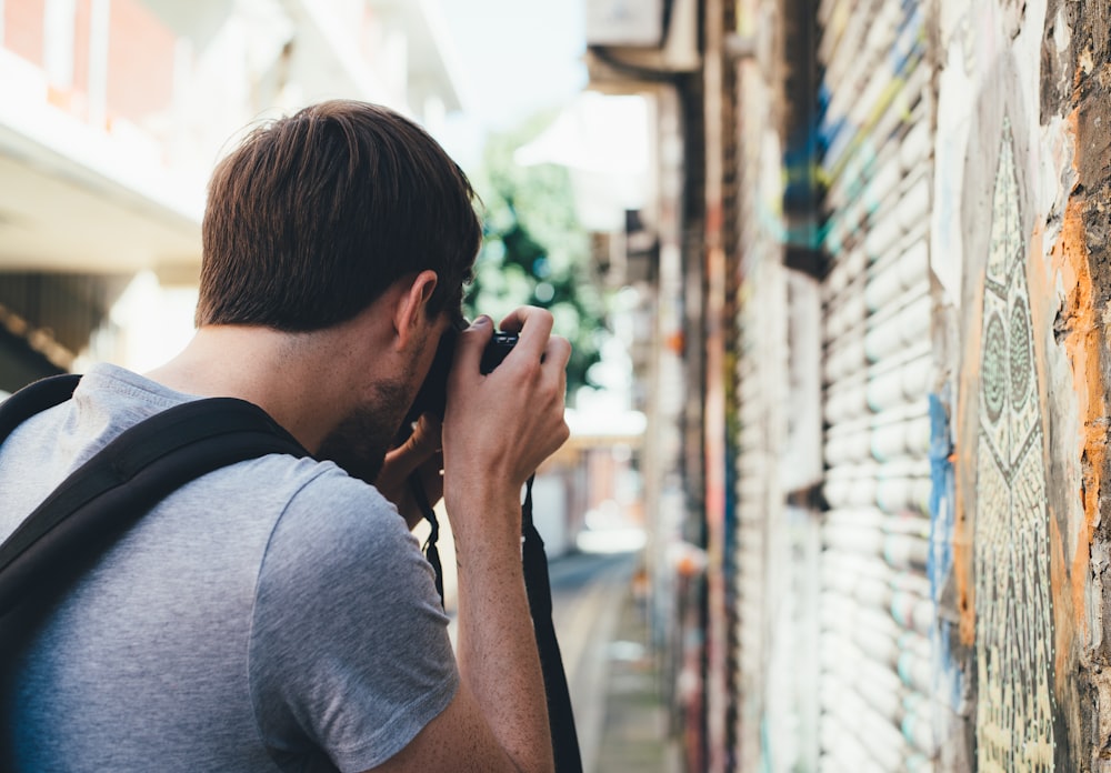 homme prenant une photo de peinture murale pendant la journée