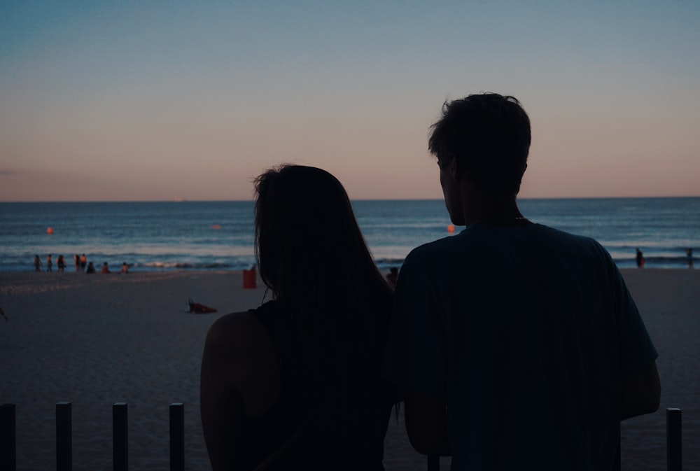 a man and a woman looking out at the ocean
