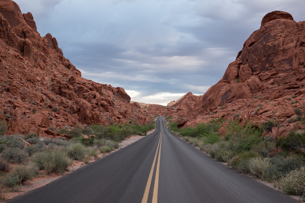 gray asphalt road between brown rock formation during daytime