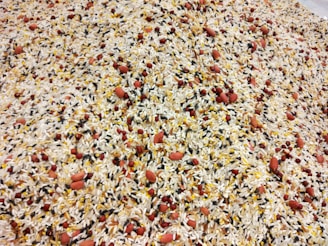A detailed mixture of various types of grains and seeds, including white rice, black rice, red beans, and peanuts, all evenly distributed and blended together.