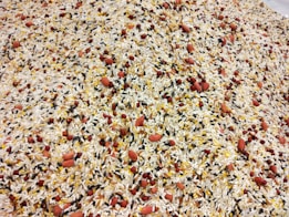 A detailed mixture of various types of grains and seeds, including white rice, black rice, red beans, and peanuts, all evenly distributed and blended together.