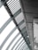 A perspective view of an architectural structure showcasing a series of curved steel beams forming an arc. The beams are complemented by slatted panels and lights attached along the interior. The image features a modern, industrial design with a focus on geometric lines and patterns.