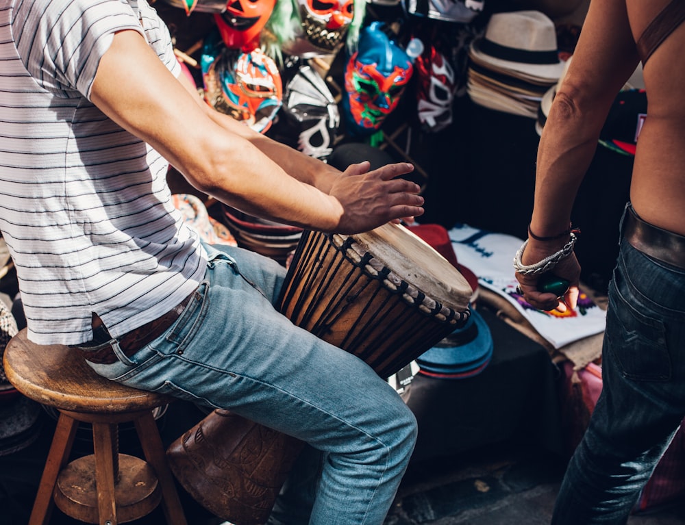 men wearing white striped shirt playing djembe