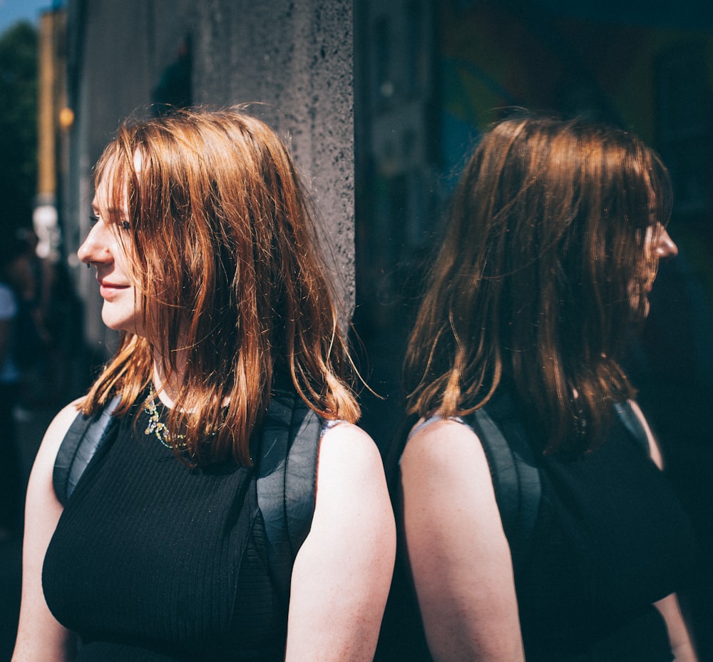 a woman in a black dress standing next to a building