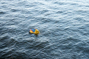 Baby floating happily in a colorful inflatable pool ring under bright sunlight.